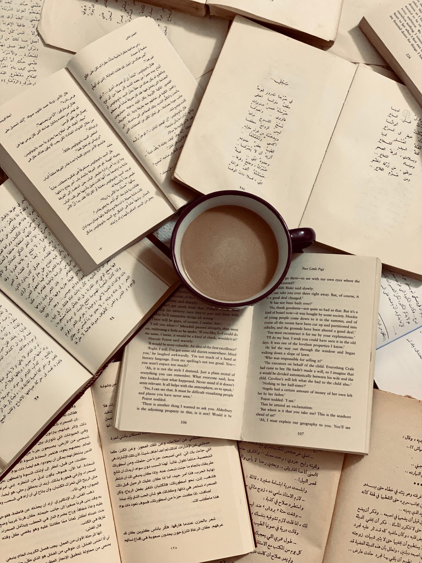A collection of open books surrounding a coffee cup, providing a cozy reading vibe.